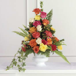 Tall mixed rose arrangement in a white vase with trailing greenery