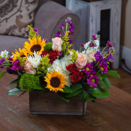 Mixed bouquet with sunflowers, roses, and chrysanthemums in a wooden box