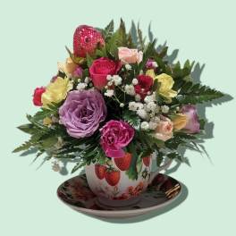 Mixed roses in a strawberry-patterned teacup on a saucer