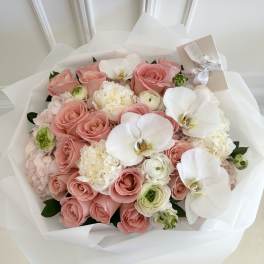 Pink rose bouquet with white orchids and cream blooms wrapped in white paper