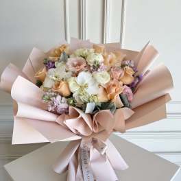 Bouquet of peach, pink, and white flowers wrapped in blush paper