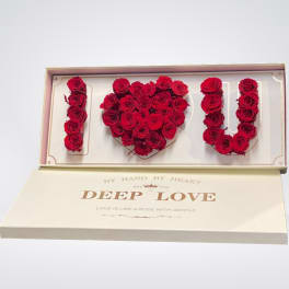 Red roses arranged to spell I love you in a gift box