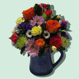 Mixed bouquet in a blue mug with orange, pink, yellow, and purple flowers