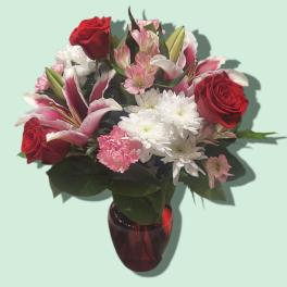 Bouquet of red roses, pink lilies, and white daisies in a red vase