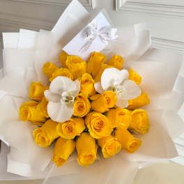 Bouquet of yellow roses with two white orchids wrapped in white paper