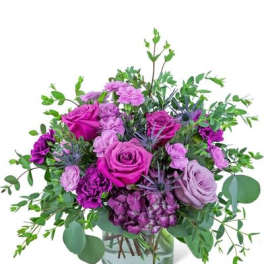 Purple roses and carnations in a glass vase with greenery