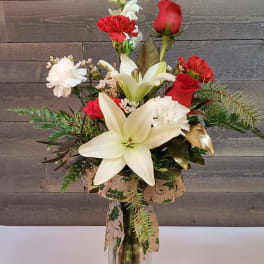 Red roses and white lilies in a glass vase with carnations