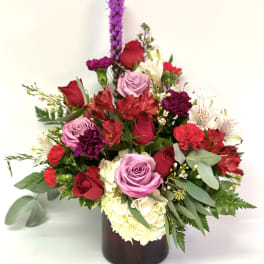 Mixed bouquet of roses, carnations, and alstroemeria in a dark vase