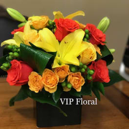 Yellow lilies and red and orange roses in a black vase
