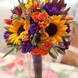 Bright bouquet of sunflowers, orange roses, and purple flowers in a vase