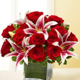 Red roses and pink lilies arranged in a square glass vase
