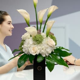 White calla lilies and roses arranged in a black vase