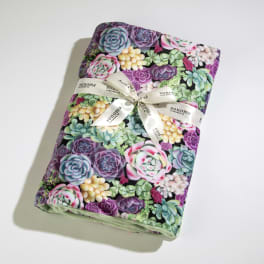 Folded blanket with colorful succulent pattern wrapped in a white Sonoma-branded ribbon