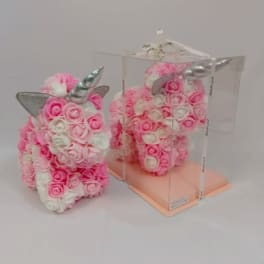 Pink and white rose-covered unicorn figurine with silver horn, one displayed in a clear gift box.