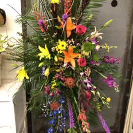 Tall tropical floral spray with lilies, roses, and orchids