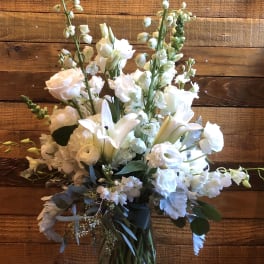 White floral arrangement in a clear glass vase with tall stems and mixed blooms
