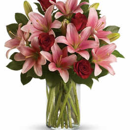 Pink lilies and red roses in a clear glass vase
