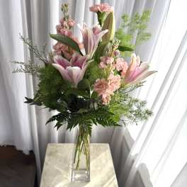 Pink lilies and carnations in a clear glass vase