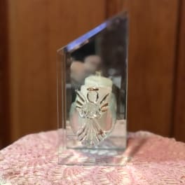 Clear glass candle holder with an angel decoration on a pink lace cloth