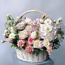 Basket of pale pink and white flowers with a woven handle