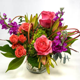 Pink and coral roses with purple flowers in a glass vase