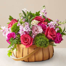Basket arrangement of pink roses and mixed blooms