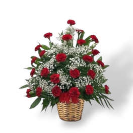 Red carnations in a woven basket with white filler flowers