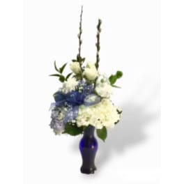 White floral arrangement in a blue glass vase with tall stems
