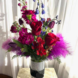 Bright mixed bouquet in a rhinestone vase with red roses and purple flowers