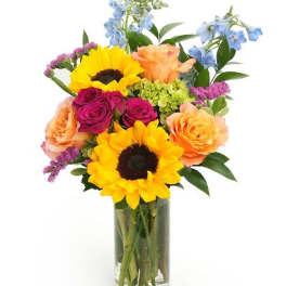 Tall glass vase of yellow sunflowers, peach and magenta roses, blue delphinium and mixed blooms