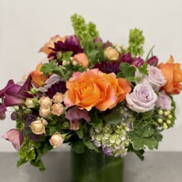 Mixed bouquet of orange and lavender roses in a glass vase