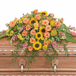 Casket spray with peach roses and yellow sunflowers