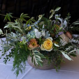 Low floral centerpiece with yellow and peach roses in a shallow bowl