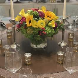 Bright yellow and magenta floral centerpiece in a glass vase on a table