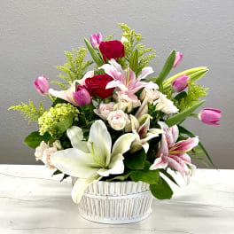 Mixed bouquet of lilies, roses, and tulips in a white basket