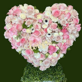 Heart-shaped pink and white rose arrangement with a "love" sign