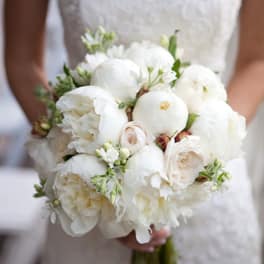 Bride holding a white bouquet of peonies and roses
