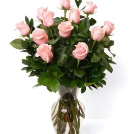 Arrangement of light pink roses in a clear glass vase with visible stems