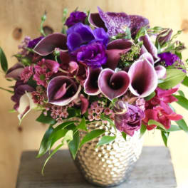 Purple and pink floral arrangement in a textured silver vase