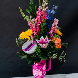 Colorful flower arrangement in a pink tumbler with a straw
