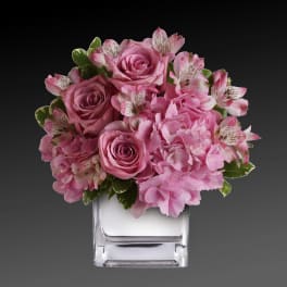 Pink roses and alstroemeria in a clear square vase