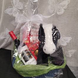 Gift basket with wine, chocolates, and a plush dog in clear wrap