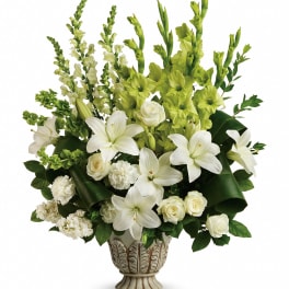 White lilies and roses arranged in a decorative vase with green flowers