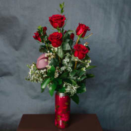 Red roses arranged in a red vase with white filler flowers