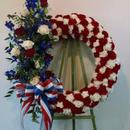Floral wreath on an easel with red and white carnations and blue roses