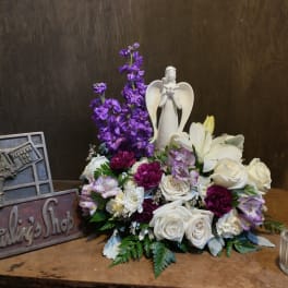 Purple and white floral arrangement with an angel figurine