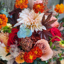 Bouquet of orange marigolds, red roses, and a pale dahlia