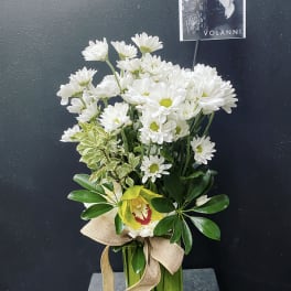 White daisies in a glass vase with a burlap ribbon