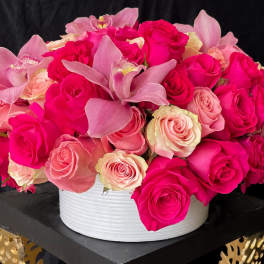 Pink and cream roses with orchid blooms in a white round vase