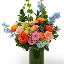 Bright mixed bouquet of roses, orchids, and hydrangea in a clear glass cylinder vase